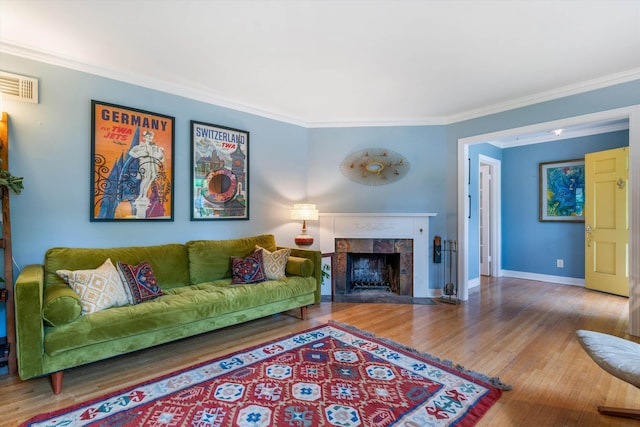 living room featuring a fireplace, wood-type flooring, and ornamental molding