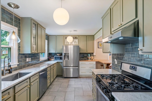 kitchen featuring sink, light stone counters, pendant lighting, stainless steel appliances, and backsplash