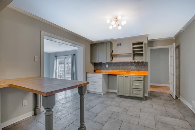 kitchen with ornamental molding, butcher block counters, built in desk, and decorative backsplash