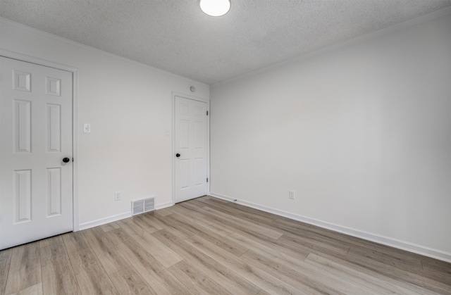 spare room with a textured ceiling and light hardwood / wood-style flooring