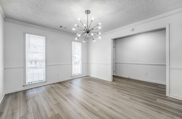 unfurnished room with light hardwood / wood-style flooring, a notable chandelier, crown molding, and a wealth of natural light