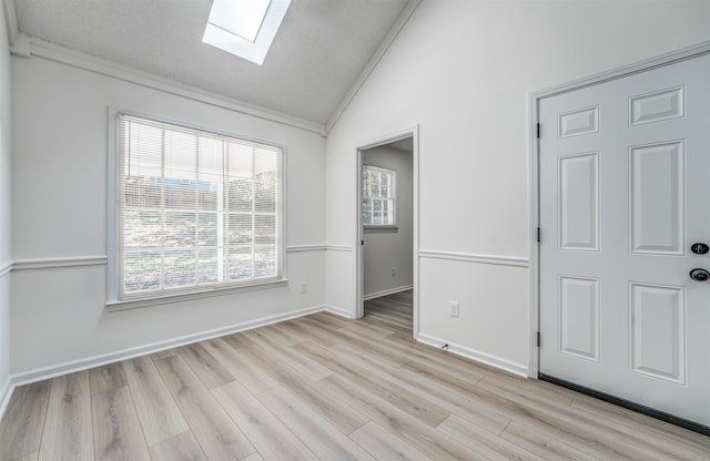 empty room with vaulted ceiling with skylight and light wood-type flooring