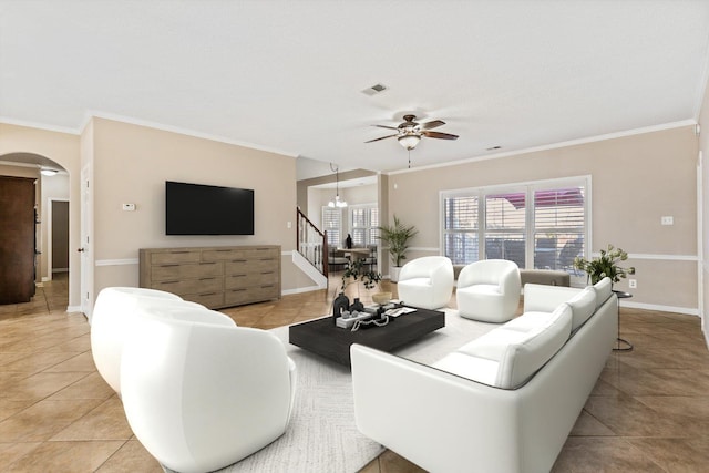 living area with arched walkways, baseboards, ornamental molding, and ceiling fan