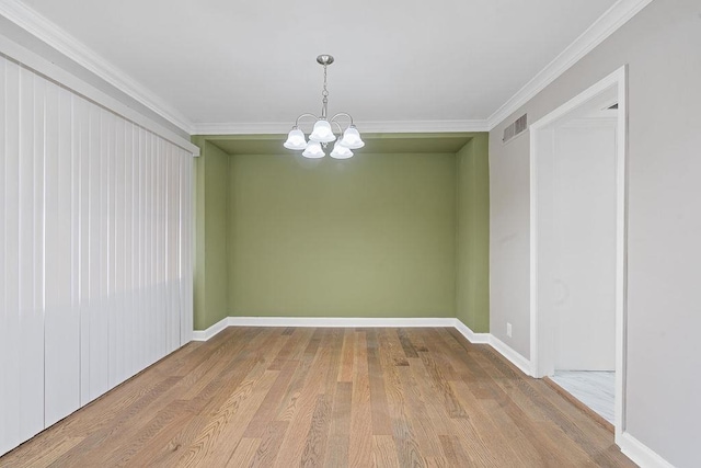 unfurnished dining area featuring crown molding, hardwood / wood-style floors, and an inviting chandelier