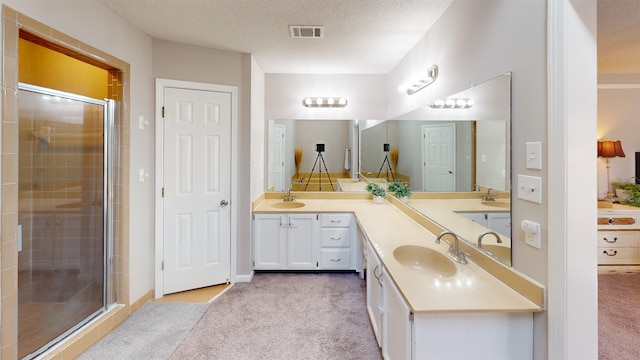 bathroom featuring vanity, an enclosed shower, and a textured ceiling