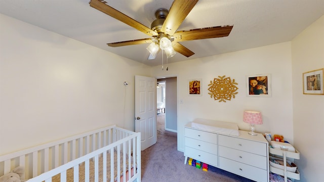 carpeted bedroom featuring a crib and ceiling fan