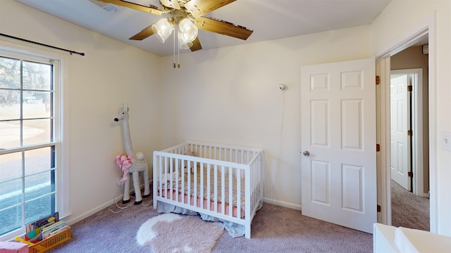 bedroom with a crib, carpet floors, and ceiling fan