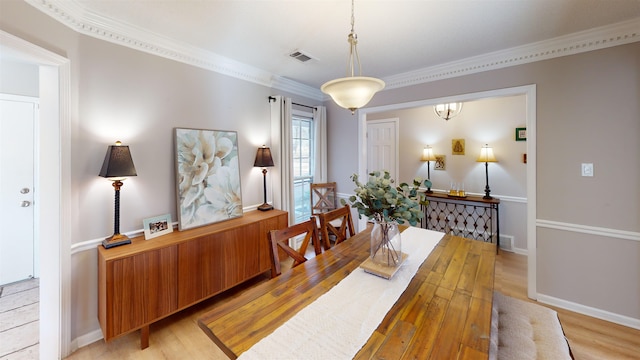 dining space with ornamental molding and light hardwood / wood-style floors