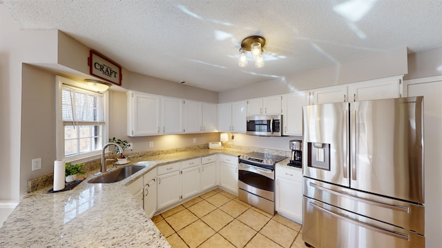 kitchen with appliances with stainless steel finishes, light stone countertops, sink, and white cabinets