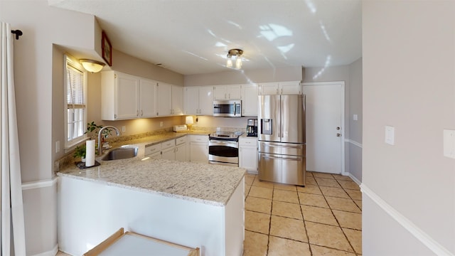 kitchen featuring sink, appliances with stainless steel finishes, light stone counters, white cabinets, and kitchen peninsula