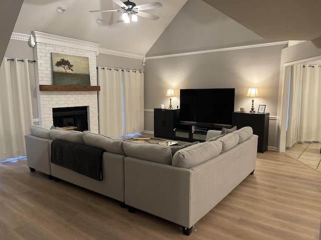 living room with crown molding, ceiling fan, a brick fireplace, and light wood-type flooring