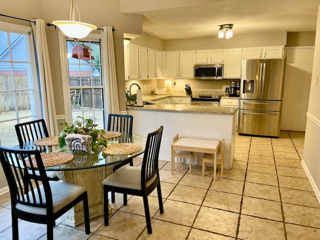 kitchen with pendant lighting, sink, white cabinets, kitchen peninsula, and stainless steel appliances