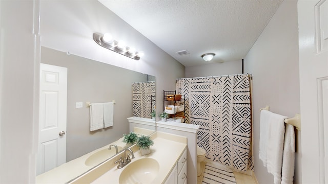 bathroom with vanity, curtained shower, toilet, and a textured ceiling