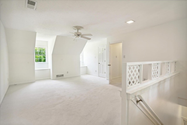 additional living space featuring light carpet and ceiling fan