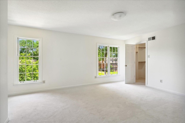 carpeted spare room with a healthy amount of sunlight and a textured ceiling