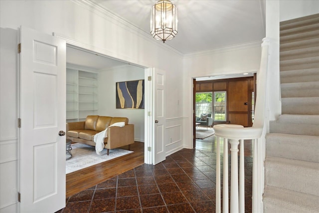 entryway with crown molding and an inviting chandelier