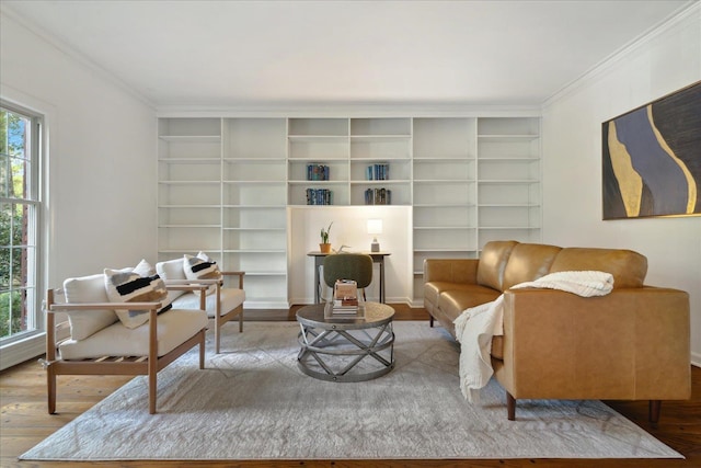 living area featuring hardwood / wood-style floors, crown molding, built in shelves, and a healthy amount of sunlight