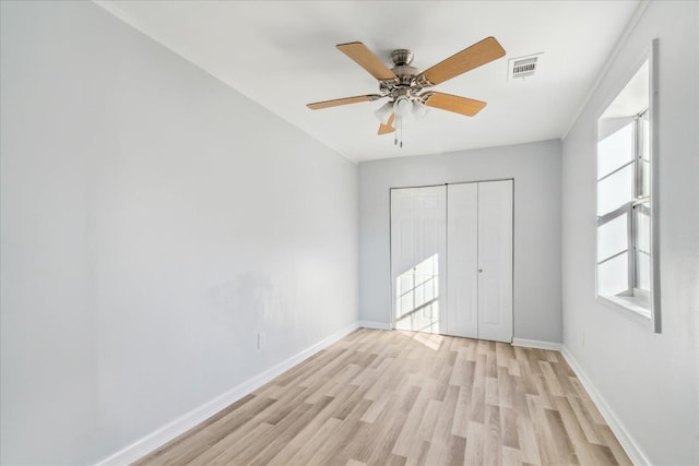 unfurnished bedroom featuring ceiling fan, light hardwood / wood-style floors, and a closet