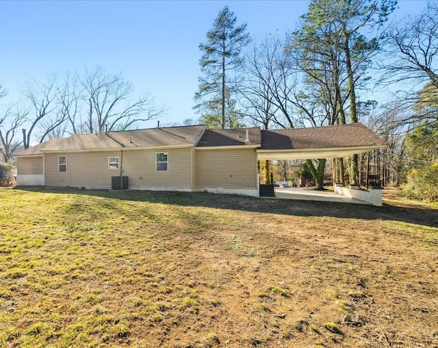 rear view of house featuring a carport, a yard, and central AC unit