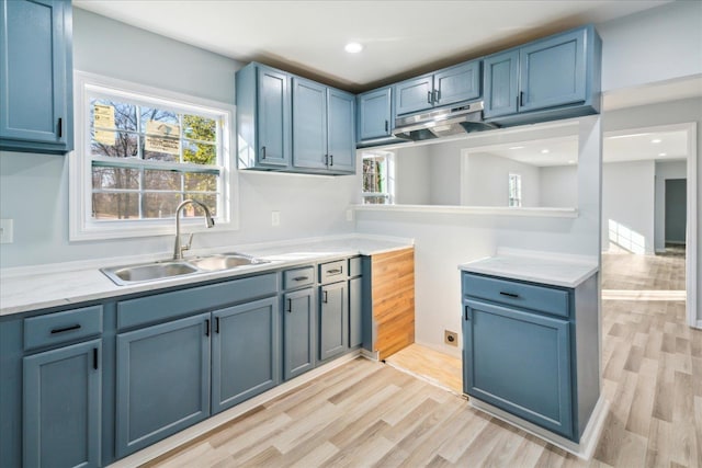 kitchen featuring blue cabinetry, sink, and light hardwood / wood-style flooring