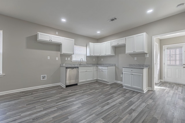 kitchen featuring hardwood / wood-style flooring, stainless steel dishwasher, light stone counters, and white cabinets