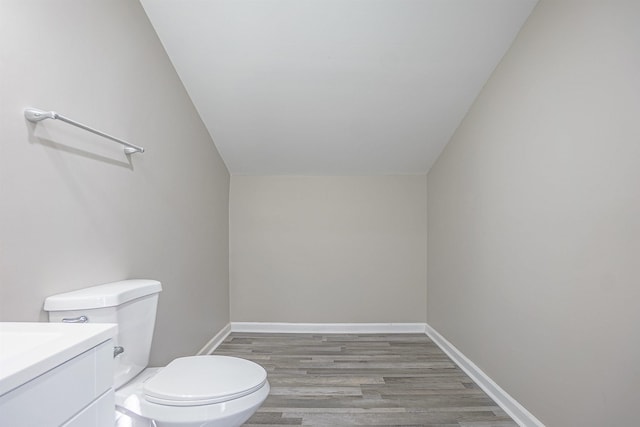 bathroom featuring vanity, hardwood / wood-style flooring, lofted ceiling, and toilet