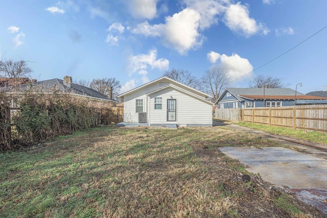 rear view of house with a patio, a yard, and central AC