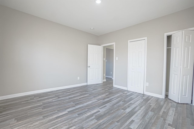 unfurnished bedroom featuring two closets and light hardwood / wood-style floors