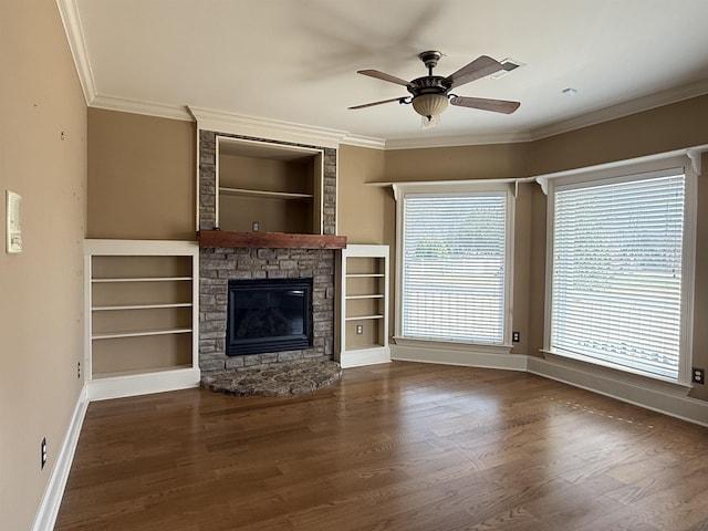 unfurnished living room with crown molding, a stone fireplace, and dark wood-type flooring