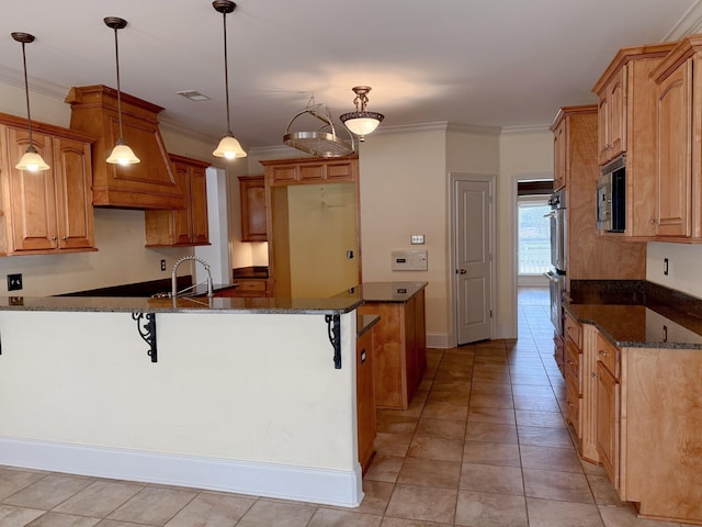 kitchen with hanging light fixtures, a breakfast bar area, and dark stone countertops