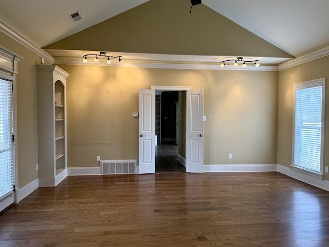 empty room featuring ornamental molding, vaulted ceiling, dark hardwood / wood-style floors, and rail lighting