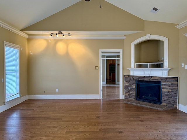 unfurnished living room with hardwood / wood-style flooring, ornamental molding, lofted ceiling, and a stone fireplace