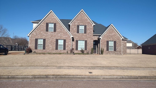 traditional home with brick siding, a shingled roof, and fence