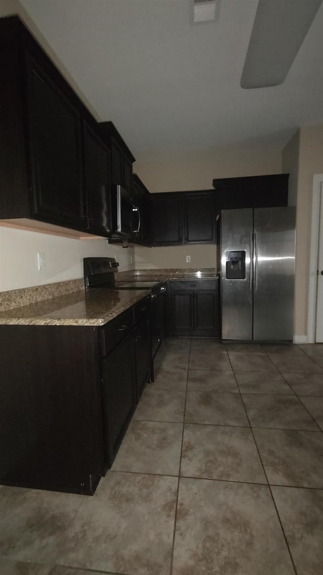 kitchen with light stone counters, black electric range, light tile patterned flooring, and stainless steel refrigerator with ice dispenser