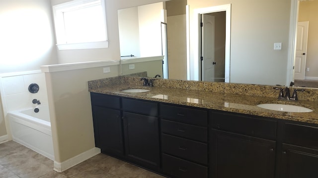 bathroom with double vanity, a garden tub, a sink, and tile patterned floors