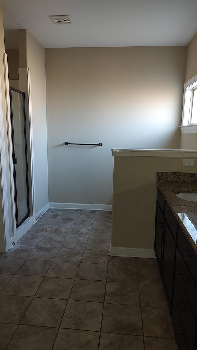 bathroom with a stall shower, visible vents, baseboards, tile patterned flooring, and vanity