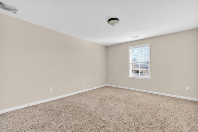 carpeted spare room with visible vents and baseboards