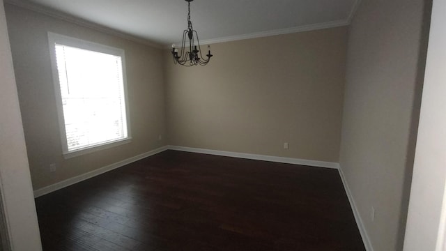 spare room featuring dark wood-style floors, ornamental molding, a notable chandelier, and baseboards