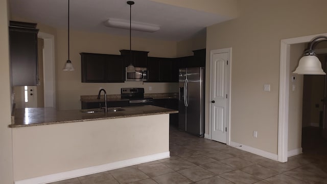 kitchen with appliances with stainless steel finishes, dark stone countertops, decorative light fixtures, a peninsula, and a sink