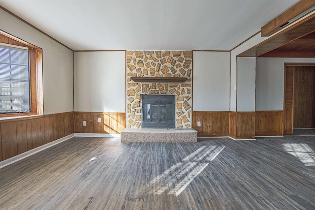 unfurnished living room with dark hardwood / wood-style floors, wooden walls, a fireplace, and crown molding