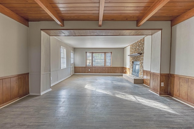 unfurnished living room featuring beamed ceiling, a stone fireplace, and wooden ceiling