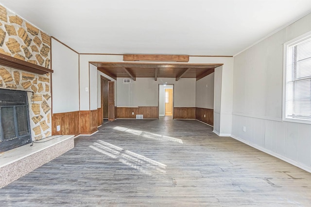 unfurnished living room with hardwood / wood-style flooring, crown molding, a fireplace, and beamed ceiling