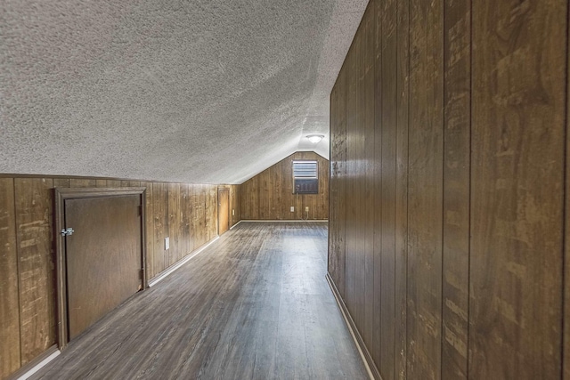 bonus room featuring dark hardwood / wood-style flooring, lofted ceiling, a textured ceiling, and wooden walls