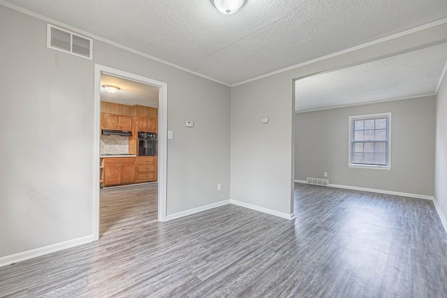 empty room featuring crown molding, wood-type flooring, and a textured ceiling