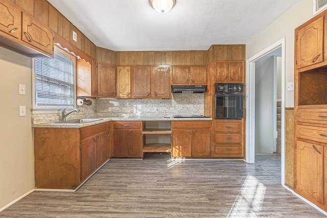 kitchen with black oven, sink, dark hardwood / wood-style flooring, decorative backsplash, and gas stovetop