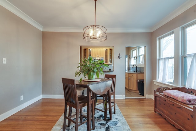 dining space featuring ornamental molding, sink, an inviting chandelier, and light hardwood / wood-style flooring