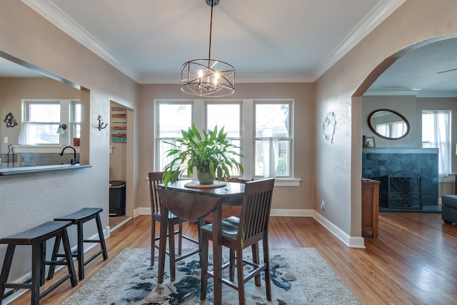 dining space with crown molding, an inviting chandelier, and light hardwood / wood-style flooring