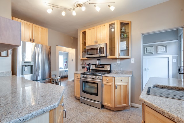 kitchen featuring light brown cabinetry, light tile patterned floors, light stone countertops, and appliances with stainless steel finishes