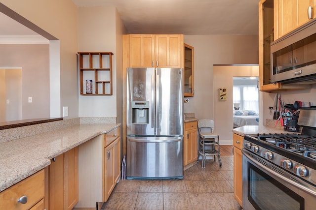 kitchen with light stone counters, stainless steel appliances, and light brown cabinetry