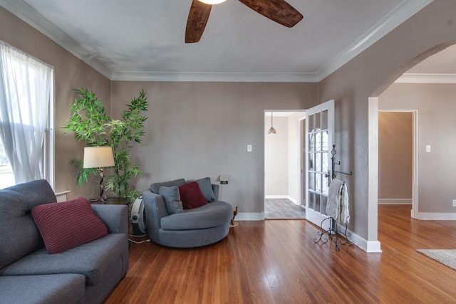 living room featuring ceiling fan, ornamental molding, and wood-type flooring